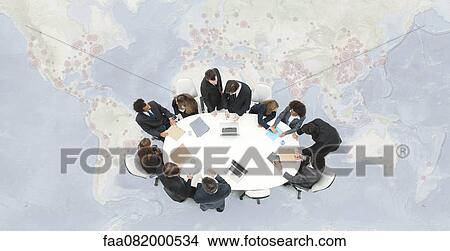 Business executives meeting on top of superimposed world map View Large Photo Image Picture - Business executives meeting on top of superimposed world map. Fotosearch