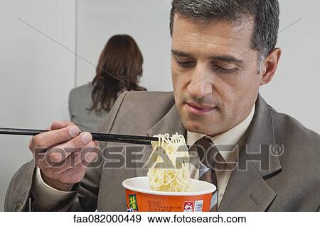 Businessman eating ramen noodles in office View Large Photo Image Stock Photo - Businessman eating ramen noodles in office. Fotosearch