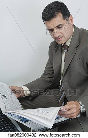 Businessman reading newspaper in office View Large Photo Image Stock Image - Businessman reading newspaper in office. Fotosearch
