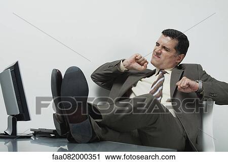Businessman sitting in office with feet up on desk View Large Photo Image Stock Image - Businessman sitting in office with feet up on desk. Fotosearch