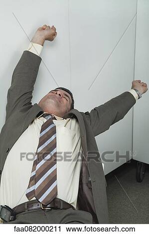 Stock Image - Businessman stretching in office. Fotosearch