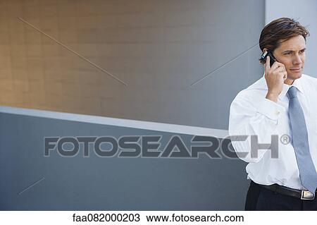 Stock Image - Businessman using cell phone outdoors. Fotosearch