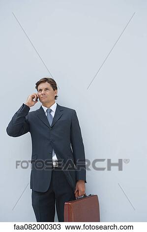 Stock Image - Businessman using cell phone outdoors. Fotosearch