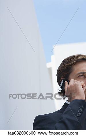 Stock Image - Businessman using cell phone outdoors, cropped. Fotosearch