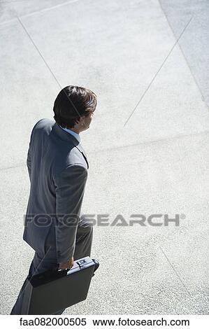 Businessman walking with briefcase in hands, elevated view View Large Photo Image Stock Photography - Businessman walking with briefcase in hands, elevated view. Fotosearch