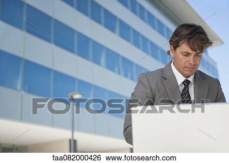 Stock Photograph - Businessman working on laptop computer outdoors. Fotosearch