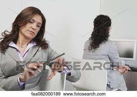 Businesswoman filing her nails at work View Large Photo Image Stock Photo - Businesswoman filing her nails at work. Fotosearch