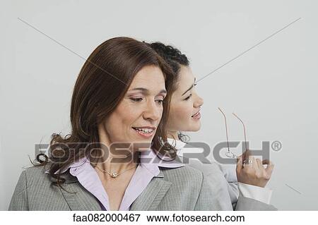 Stock Photo - Businesswomen gossiping together. Fotosearch