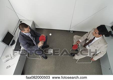 Colleagues hitting ping pong ball back and forth in office cubicle View Large Photo Image Stock Image - Colleagues hitting ping pong ball back and forth in office cubicle. Fotosearch