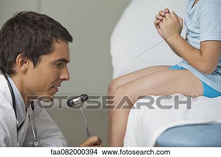 Picture - Doctor checking boy's reflexes with reflex hammer, side view, cropped. Fotosearch