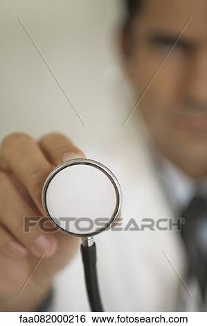 Stock Photograph - Doctor holding stethoscope, focus on foreground. Fotosearch