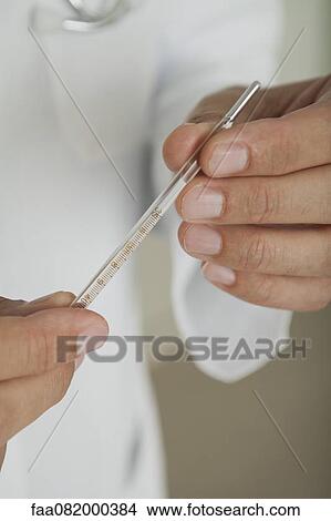 Picture - Doctor holding thermometer, cropped. Fotosearch