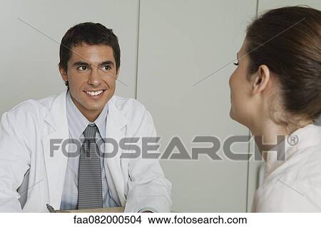 Picture - Doctor sitting across from female patient. Fotosearch