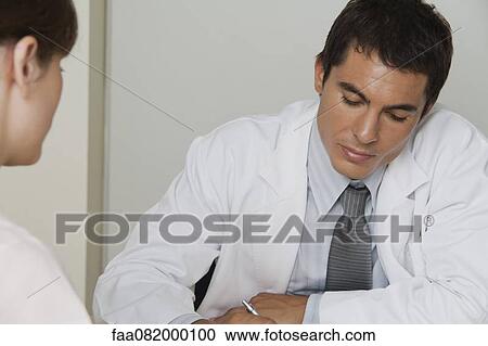 Doctor sitting across from female patient, writing prescription View Large Photo Image Stock Image - Doctor sitting across from female patient, writing prescription. Fotosearch