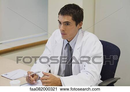 Stock Image - Doctor sitting in office. Fotosearch