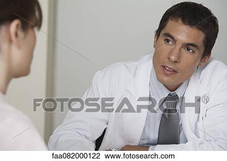 Stock Image - Doctor talking with female patient. Fotosearch