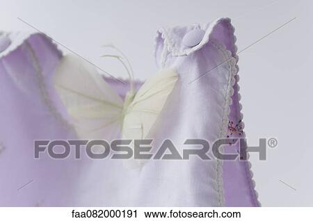 Stock Image - Fake butterfly resting on baby clothing. Fotosearch