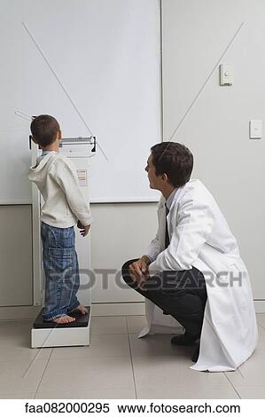 Little boy standing on weight scale in doctor's office View Large Photo Image Stock Photography - Little boy standing on weight scale in doctor's office. Fotosearch