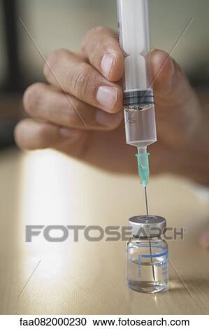 Man filling syringe from vial View Large Photo Image Stock Image - Man filling syringe from vial. Fotosearch