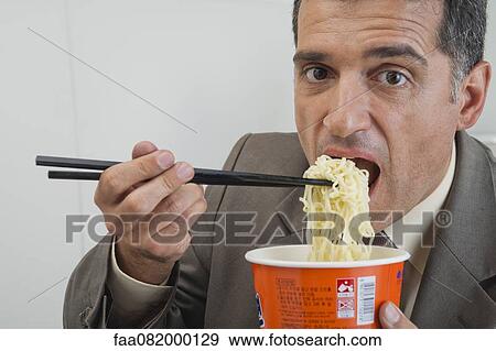 Stock Photo - Mature businessman eating ramen noodles. Fotosearch