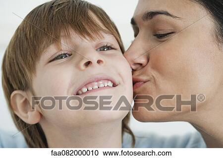 Stock Image - Mother kissing boy's cheek. Fotosearch