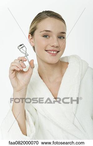 Stock Image - Preteen girl holding eyelash curler. Fotosearch