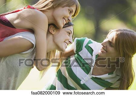 Smiling young women, one woman giving another piggyback ride View Large Photo Image Stock Photo - Smiling young women, one woman giving another piggyback ride. Fotosearch