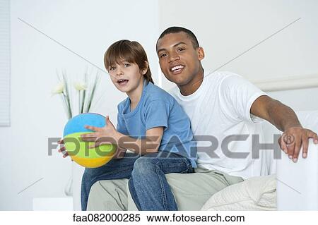 Stock Photography - Son sitting on father's lap. Fotosearch