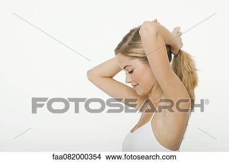 Picture - Teen girl putting her hair in a ponytail, side view. Fotosearch