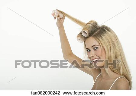 Stock Image - Teen girl rolling her hair with curlers. Fotosearch