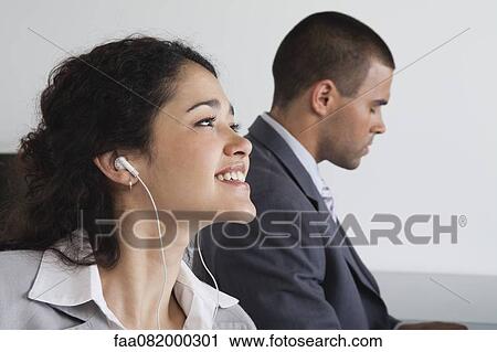 Woman listening to earphones and daydreaming in office View Large Photo Image Stock Image - Woman listening to earphones and daydreaming in office. Fotosearch