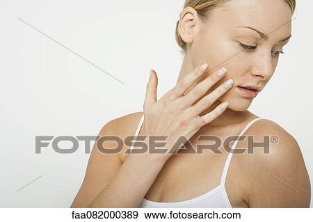 Woman touching her cheek, looking over shoulder View Large Photo Image Stock Photo - Woman touching her cheek, looking over shoulder. Fotosearch