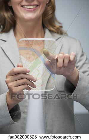 Woman using touch screen technology to view map on transparent digital tablet View Large Photo Image Stock Photography - Woman using touch screen technology to view map on transparent digital tablet. Fotosearch