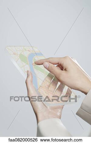 Stock Photograph - Woman using transparent digital tablet with touch screen to view map, cropped. Fotosearch