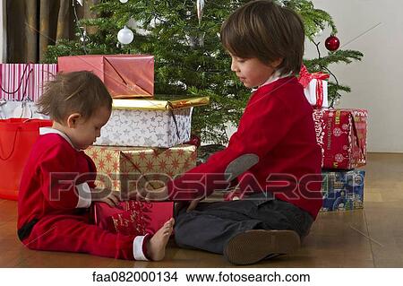 Young brother and sister opening Christmas gift together View Large Photo Image Picture - Young brother and sister opening Christmas gift together. Fotosearch