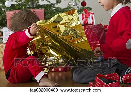 Stock Photo - Young brother and sister opening Christmas gifts together. Fotosearch
