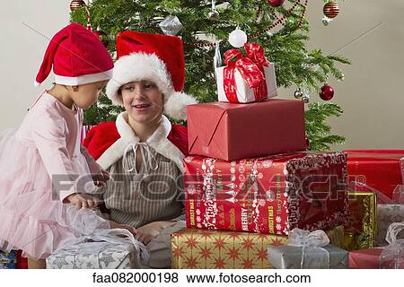 Stock Photo - Young brother and sister preparing to open Christmas presents. Fotosearch