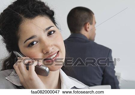 Stock Photo - Young businesswoman using cell phone in office. Fotosearch