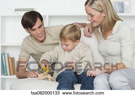Stock Image - Young parents watching as little boy plays with toys. Fotosearch