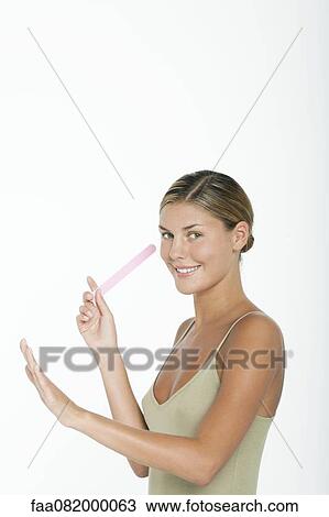 Stock Image - Young woman filing her nails. Fotosearch