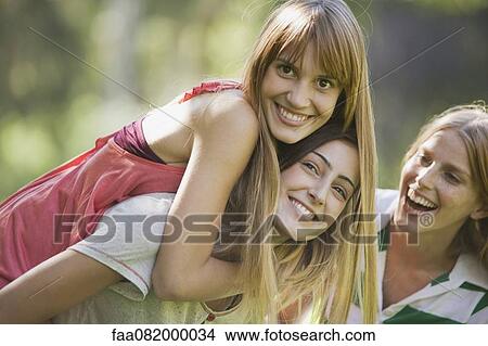 Young woman giving girlfriend piggyback ride View Large Photo Image Picture - Young woman giving girlfriend piggyback ride. Fotosearch