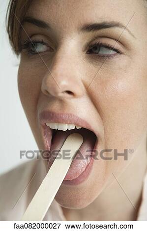 Young woman having mouth examined with tongue depressor View Large Photo Image Stock Photo - Young woman having mouth examined with tongue depressor. Fotosearch