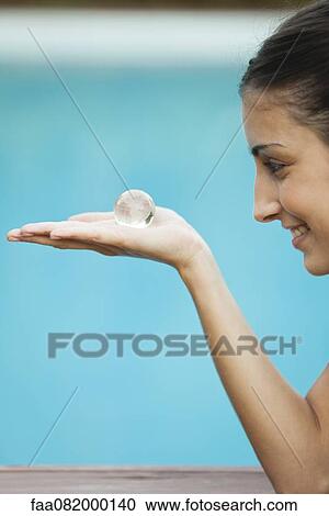 Young woman holding crystal globe in palm, side view View Large Photo Image Stock Image - Young woman holding crystal globe in palm, side view. Fotosearch