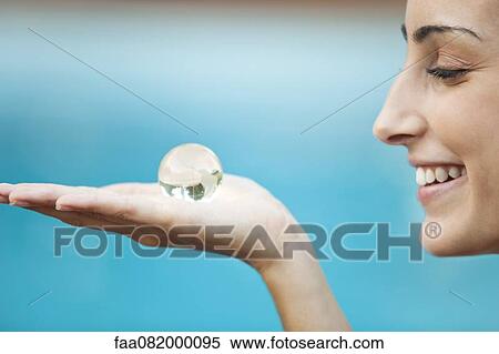 Young woman holding crystal globe in palm, side view View Large Photo Image Stock Photography - Young woman holding crystal globe in palm, side view. Fotosearch