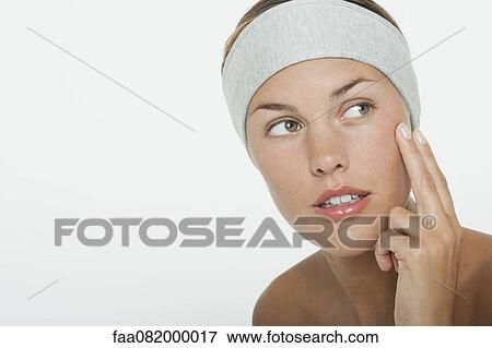 Stock Photo - Young woman moisturizing her face. Fotosearch