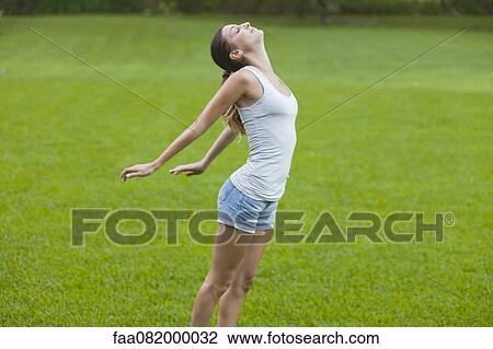 Young woman taking deep breath with arms and head back View Large Photo Image Stock Image - Young woman taking deep breath with arms and head back. Fotosearch