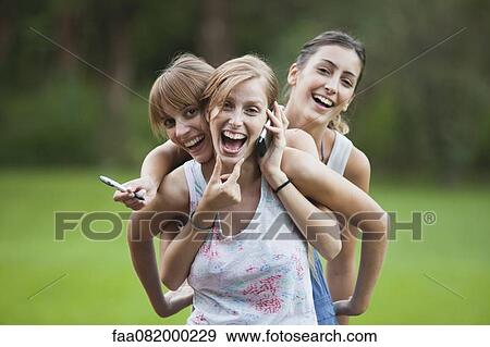 Stock Photo - Young women together outdoors, smiling. Fotosearch