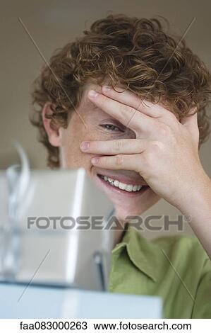 Stock Image - Boy with pile of presents, peeking out between fingers. Fotosearch