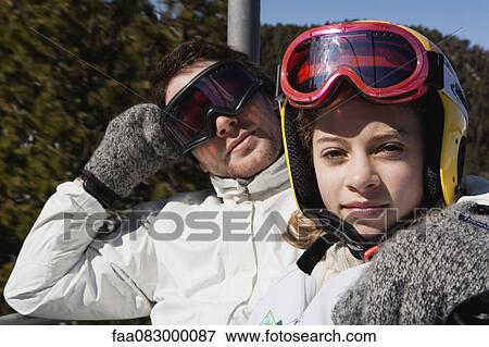 Stock Photo - Brother and younger sister on chair lift, portrait. Fotosearch