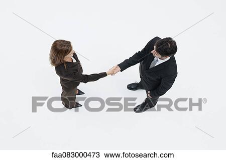 Stock Image - Business associates shaking hands, overhead view. Fotosearch